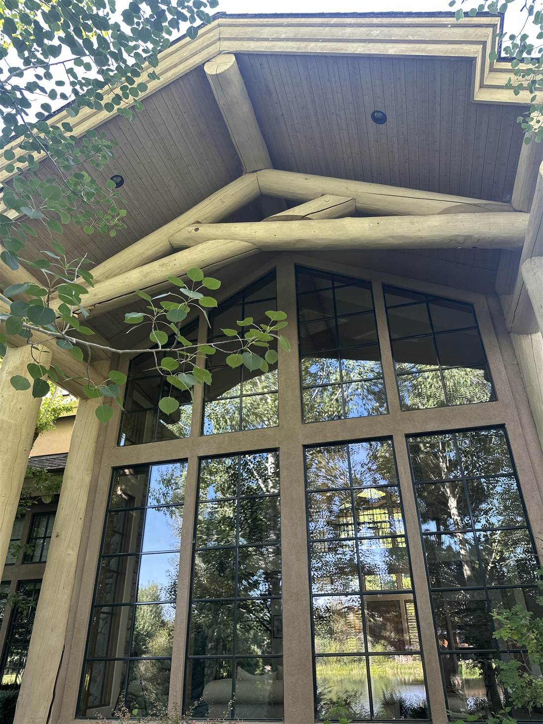 Massive log entry trusses over a two-story window wall on a luxury log home